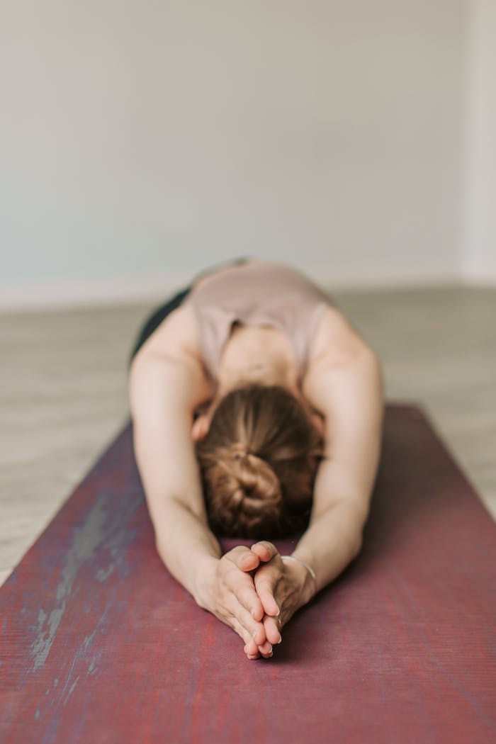 A woman stretches in Child's Pose during a yoga session, promoting wellness and relaxation.