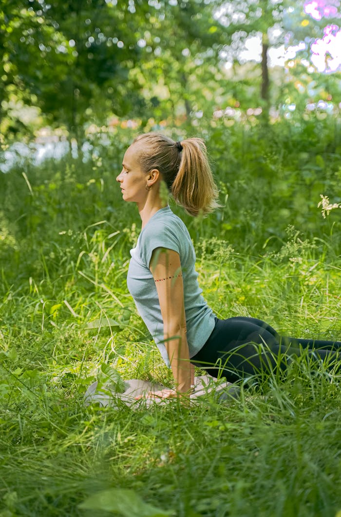 Woman practicing yoga on a mat in a serene outdoor setting, embodying healthy lifestyle.